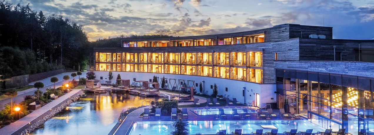 Beleuchtete Poollandschaft und Hotelanlage in der Abenddämmerung im Wellnesshotel Reischlhof